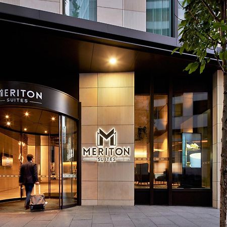 Meriton Suites Sussex Street, Sídney Exterior foto The photo shows the entrance of a hotel or suite establishment named "Meriton Suites." The entrance features a revolving door and a large, illuminated sign with the name "MERITON SUITES." The facade is modern and sleek, with a combination of glass an