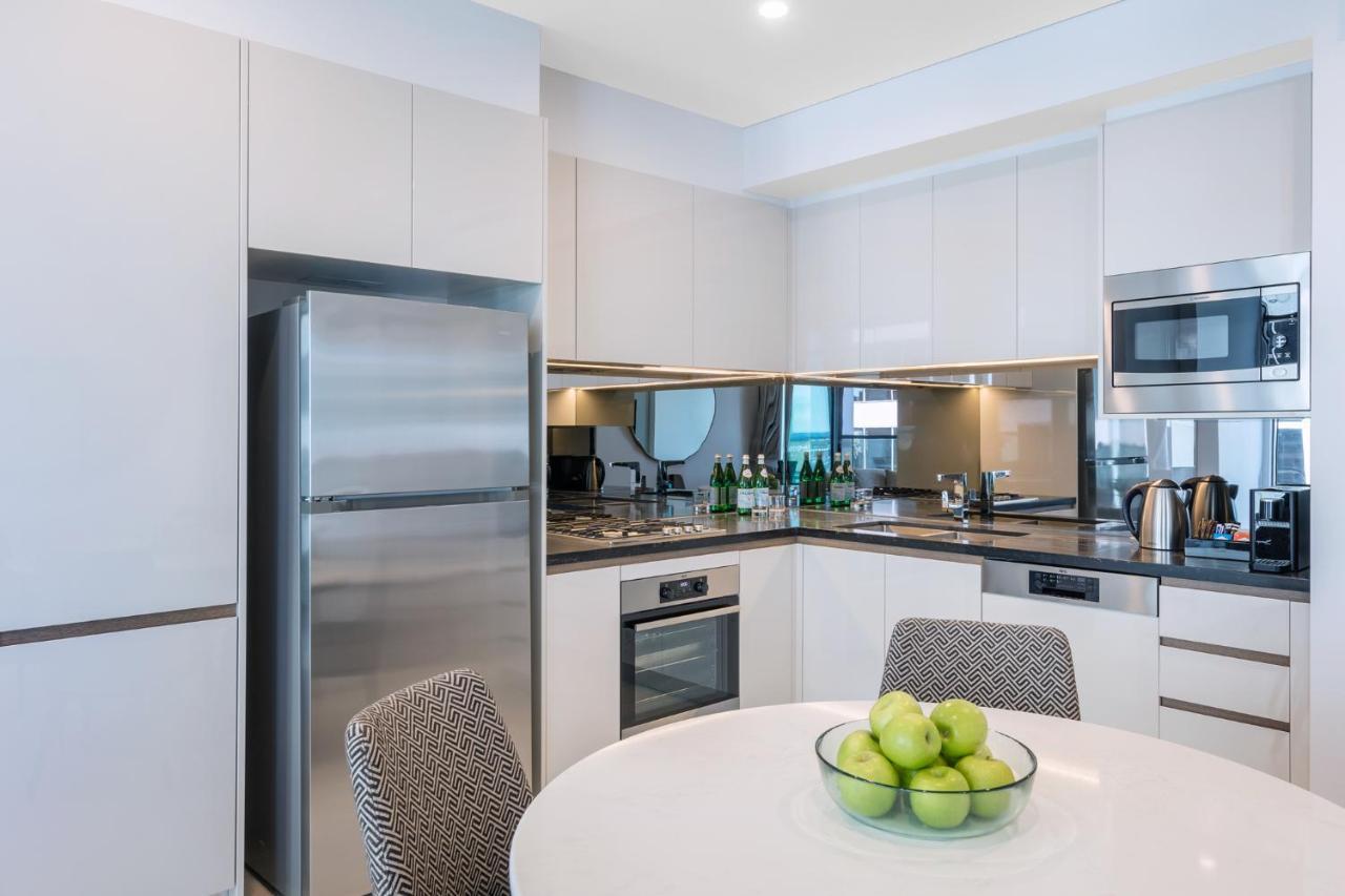 Meriton Suites Sussex Street, Sídney Exterior foto The photo displays a modern kitchen with a sleek design. It features light-colored cabinetry and a countertop with a polished finish. On the left, there is a stainless steel refrigerator. The kitchen is equipped with various appliances, including an 