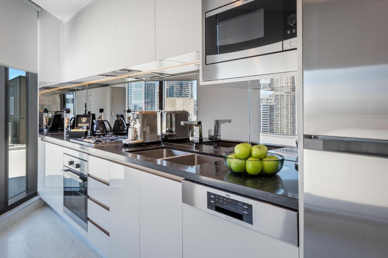 Meriton Suites Sussex Street, Sídney Exterior foto The photo shows a modern kitchen featuring sleek cabinetry and stainless steel appliances. There is a glossy countertop with a bowl of green apples as a decoration. The kitchen includes a built-in oven, a microwave, and other kitchen gadgets, along w