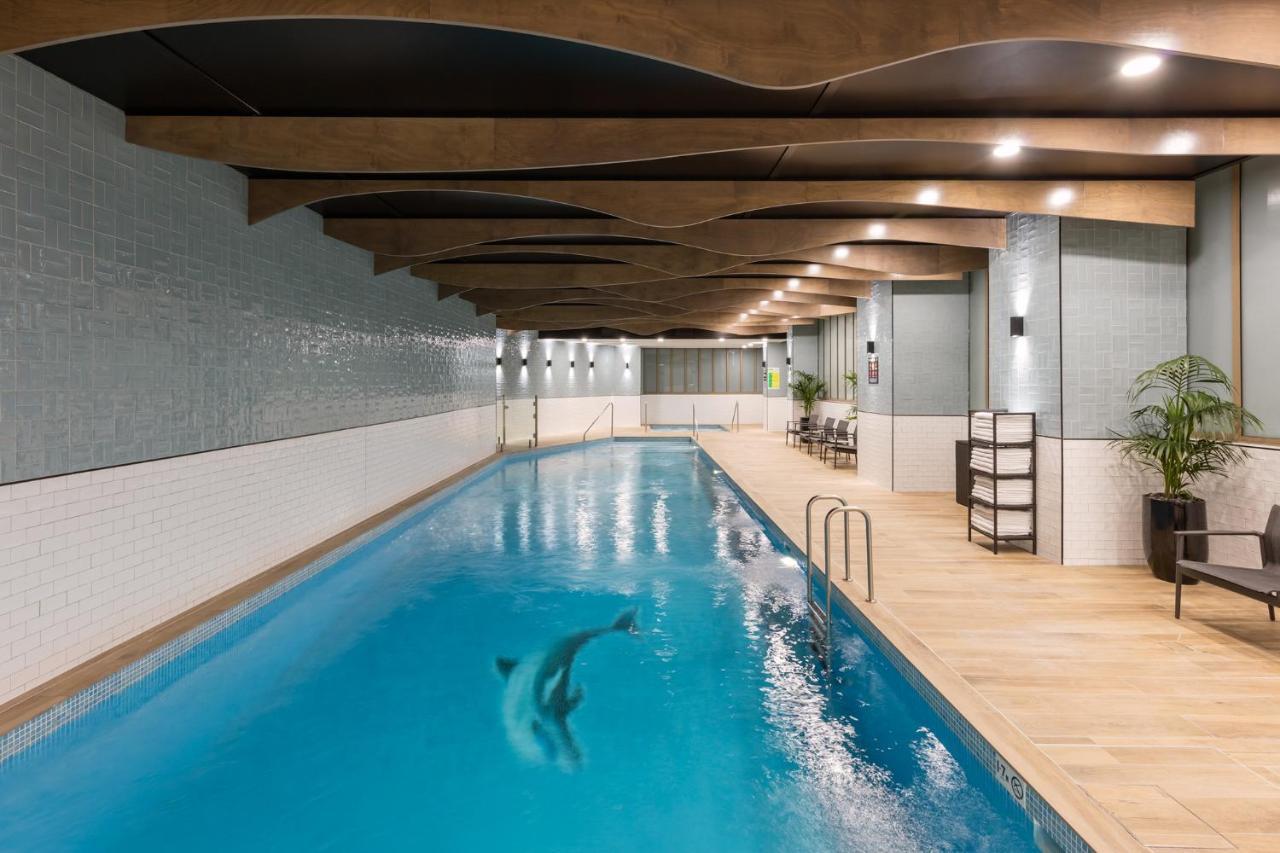 Meriton Suites Sussex Street, Sídney Exterior foto The photo shows an indoor swimming pool. The pool features clear blue water, and there is a dolphin swimming in it. The surrounding area has a modern design with curved wooden beams on the ceiling, and the walls are tiled in light colors. There are a