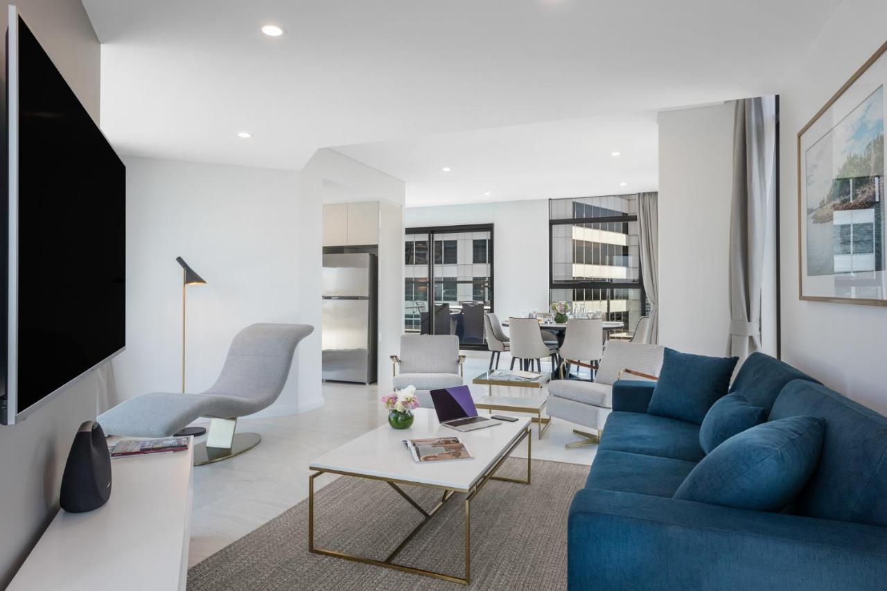 Meriton Suites Sussex Street, Sídney Exterior foto The photo shows a modern living space that features a bright and stylish interior. Key elements include:

- A sleek blue sofa and a light gray lounge chair, providing comfortable seating.
- A coffee table with a minimalist design, positioned in front