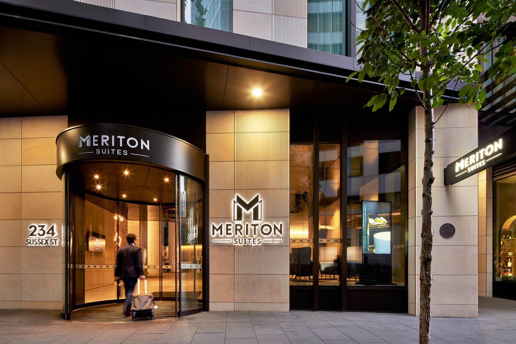 Meriton Suites Sussex Street, Sídney Exterior foto The photo shows the entrance of a hotel or suite establishment named "Meriton Suites." The entrance features a revolving door and a large, illuminated sign with the name "MERITON SUITES." The facade is modern and sleek, with a combination of glass an